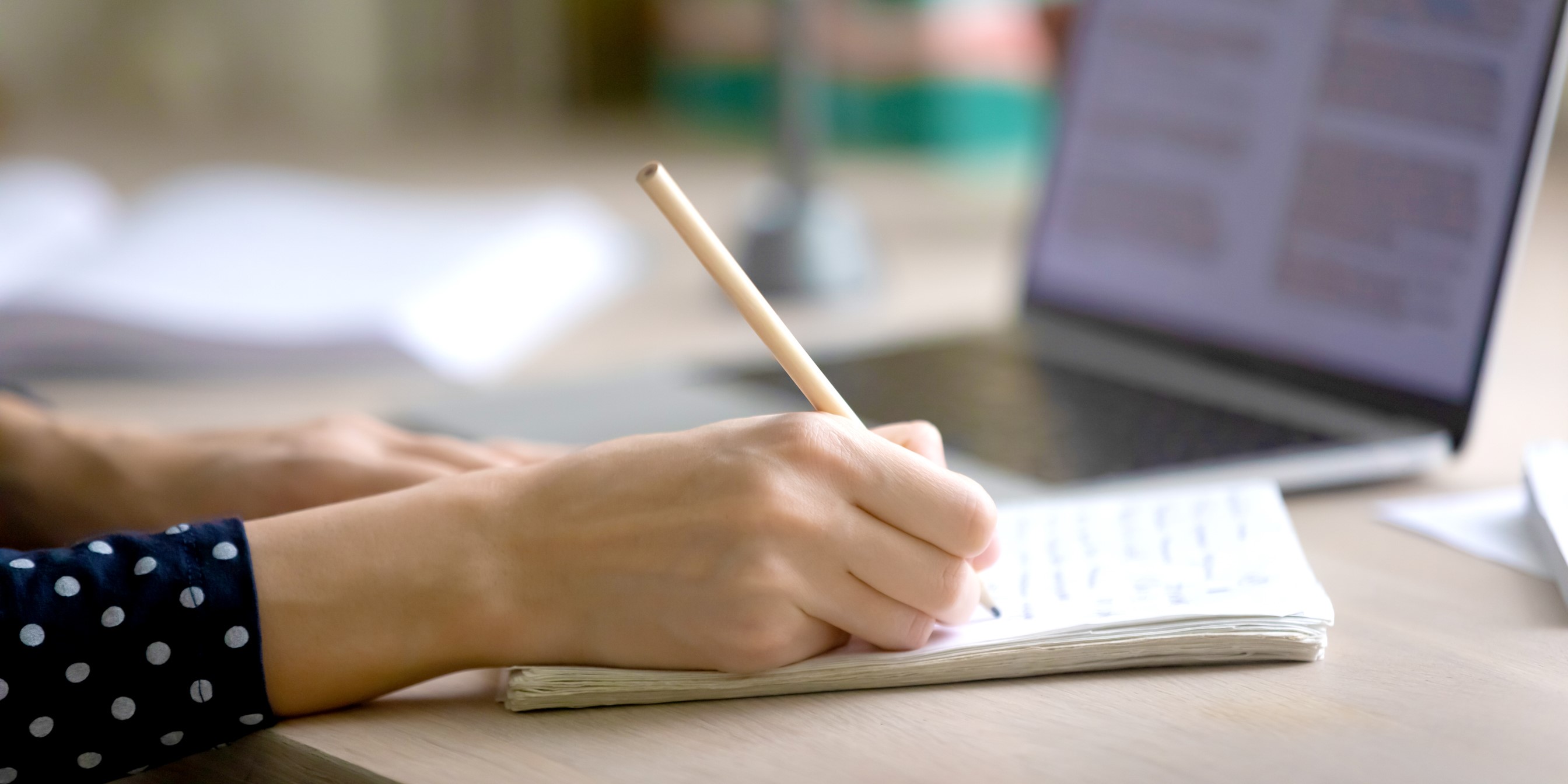 Hand holding a pencil writing on a notebook