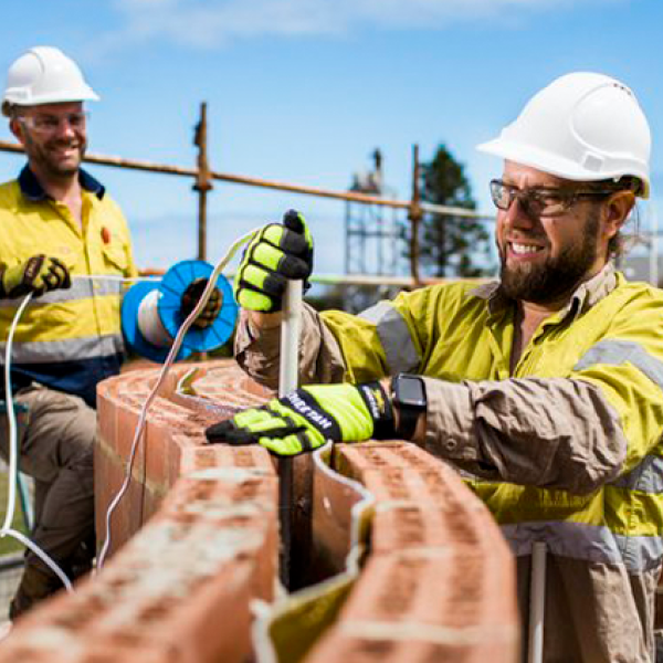 Two workers drilling into brick